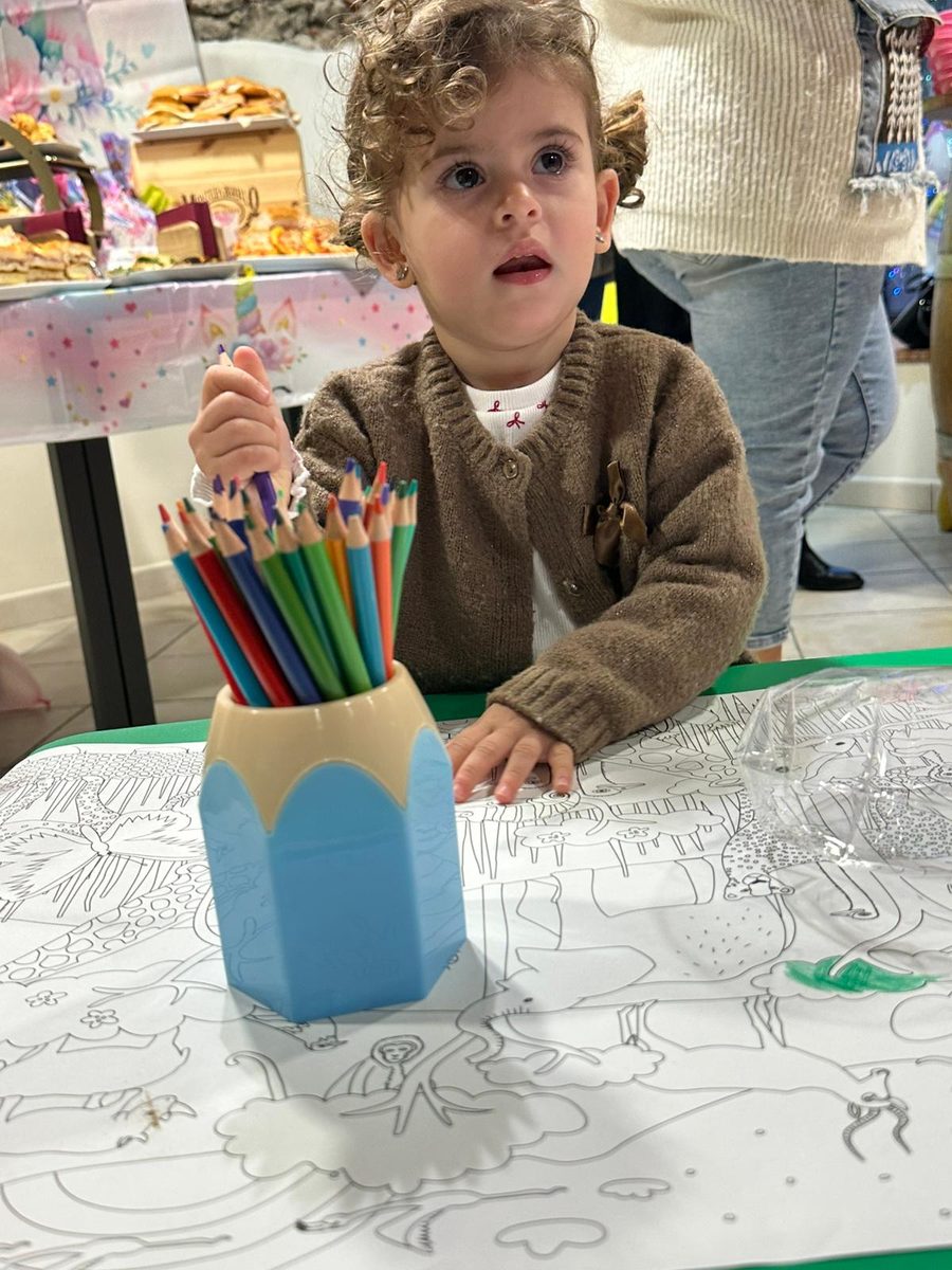 Bambina che colora al tavolo durante una festa al Kids Club
